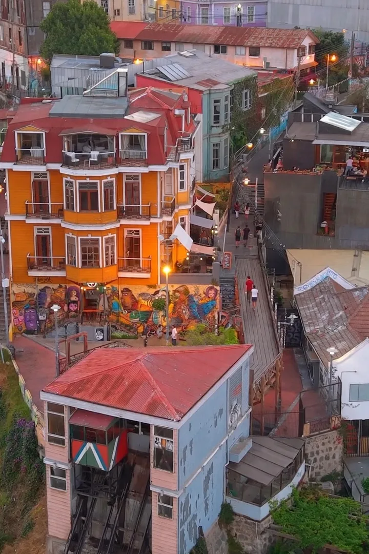 La casona amarilla de Casa Vander en el Cerro Alegre, junto a la estación del ascensor Reina Victoria, al atardecer.